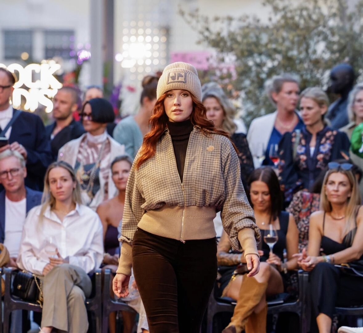 Marit on the runway in a knit beanie, front row visible