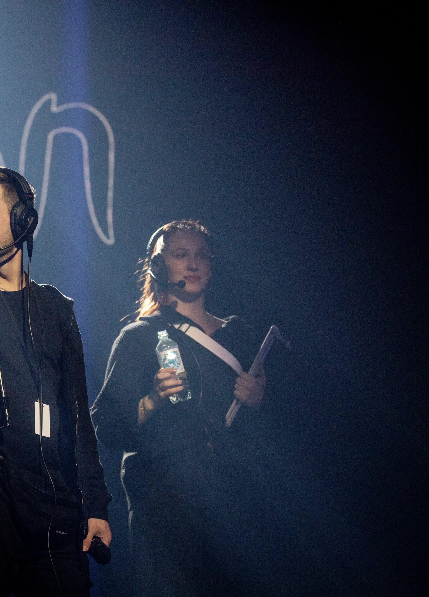 Marit with a headset, directing a performer in the dark